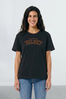 Woman wearing a black t-shirt with 'VELVET' text on a light background