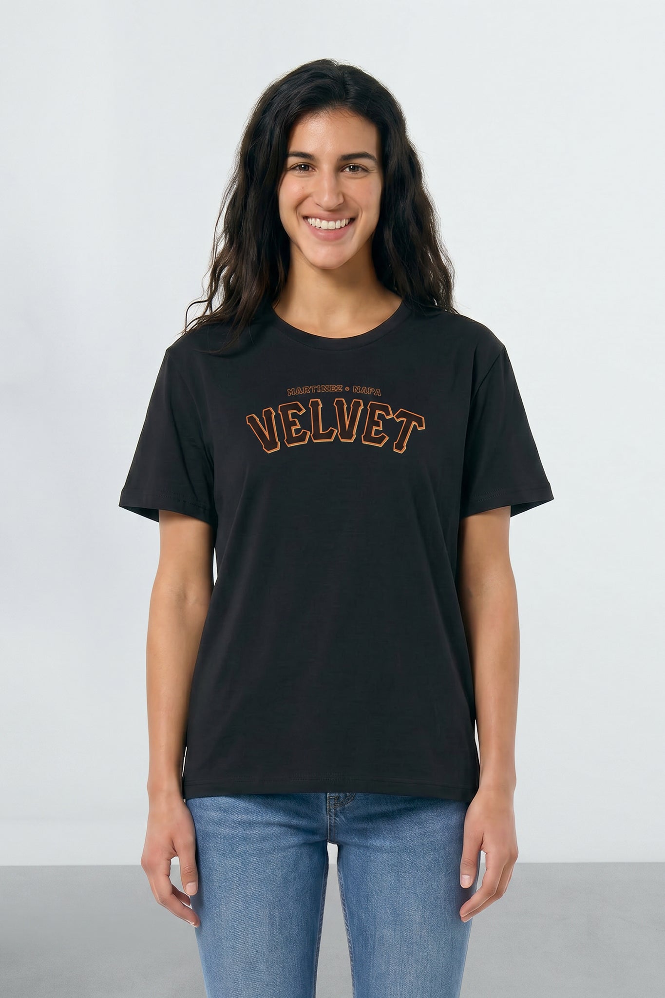 Woman wearing a black t-shirt with 'VELVET' text on a light background