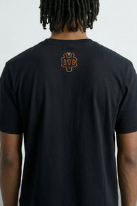 Person wearing a black t-shirt with a logo on the back against a light background