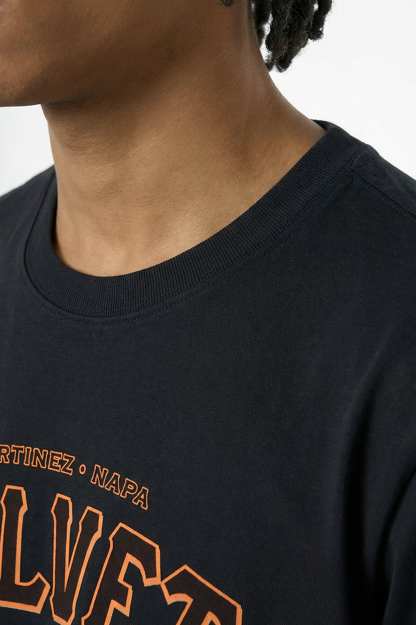 Black t-shirt with orange text worn by a person on a light background