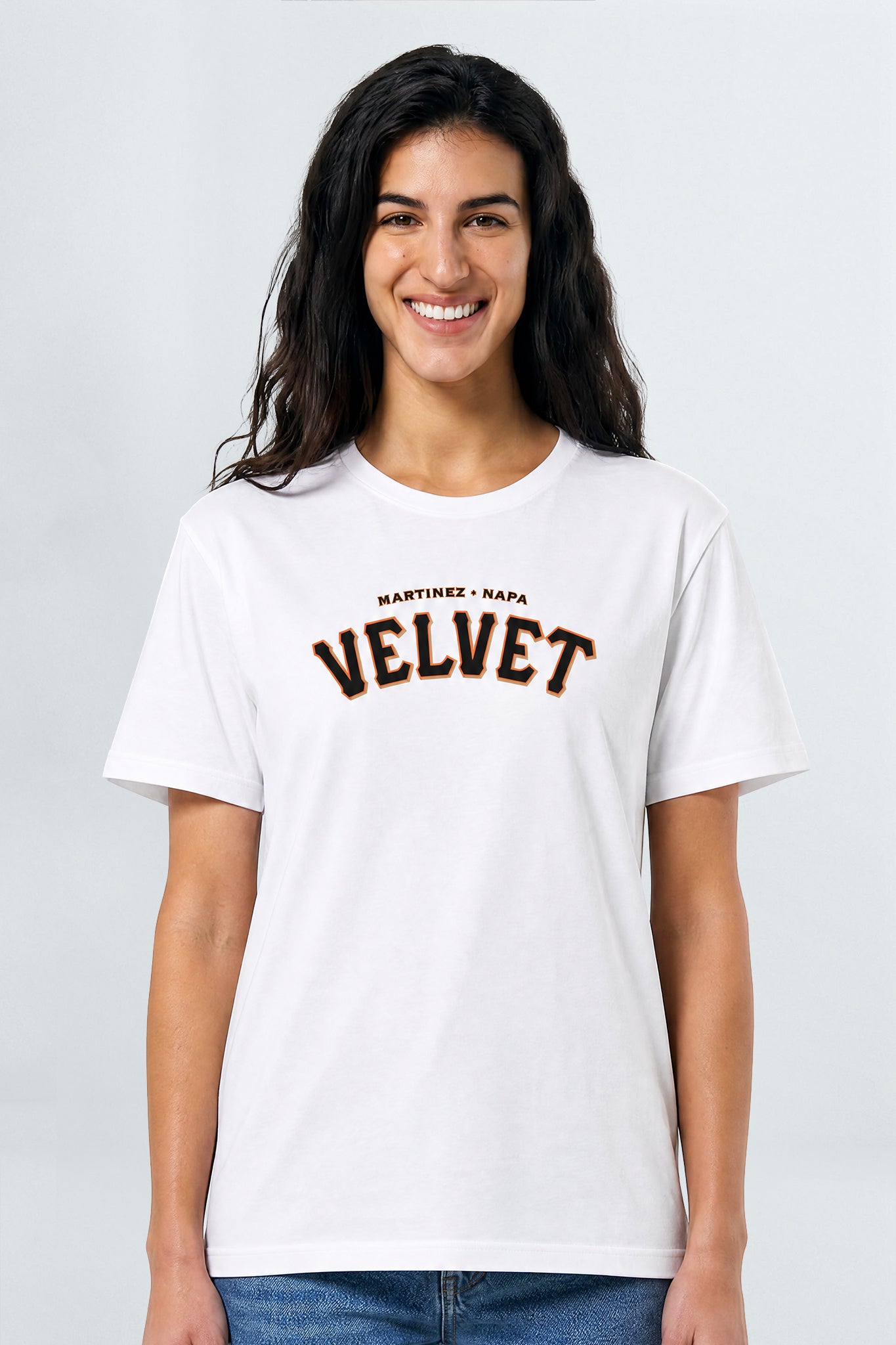 Woman wearing a white t-shirt with 'Velvet' printed on it against a plain background