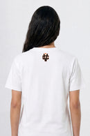 Person wearing a white t-shirt with a logo on the back against a plain background