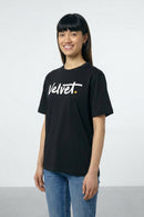 Person wearing a black t-shirt with 'Velvet' logo on a light background